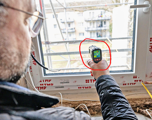Ein Techniker misst die Temperatur eines eingebauten Heizglas-Fensters.