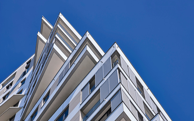 159 Schiebeläden mit feststehenden ­Lamellen der Modellvariante SunMax 37 in elegantem Weißaluminium (RAL 9006) ­bilden einen ruhigen Kontrast zu den topasfarbenen und weißen Fassadentafeln. So ­erscheint die Sonnenschutzanlage nicht als technisches Zusatzelement, sondern als integraler Bestandteil der Fassadengestaltung.
