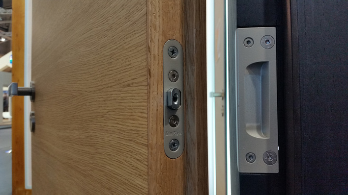 Mit einer externen Bandseitensicherung lassen sich Eingangstüren für die Widerstandsklasse RC3 sichern. Die Lösung von Basys wird flügelseitig mit einem entsprechenden Gegenstück in der Zarge montiert und bleibt für die sichere Verbindung justierbar.